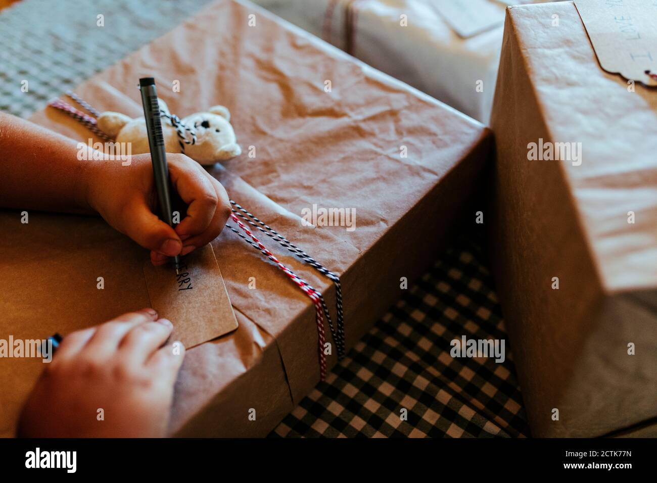 Hands of boy writing on Christmas gift at home Stock Photo