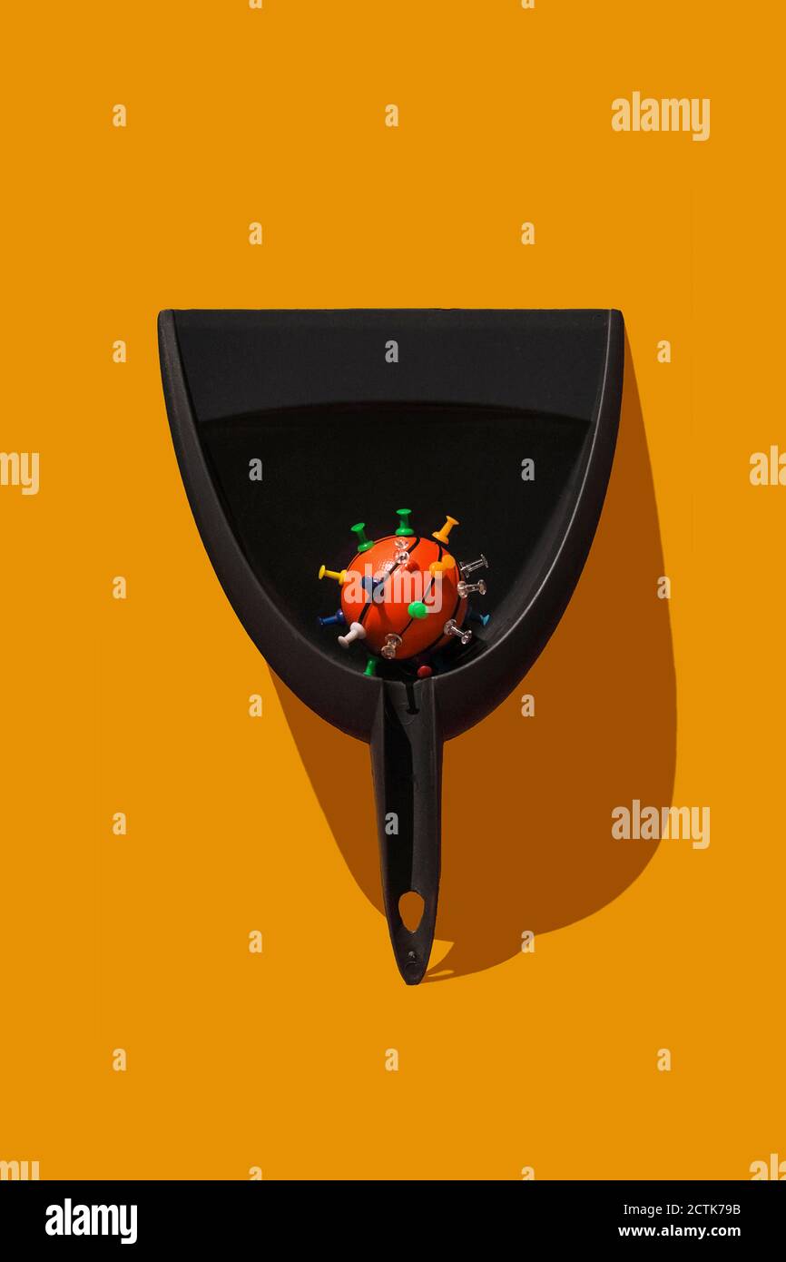 Studio shot of dustpan with thumbtacked basketball resembling virus cell Stock Photo