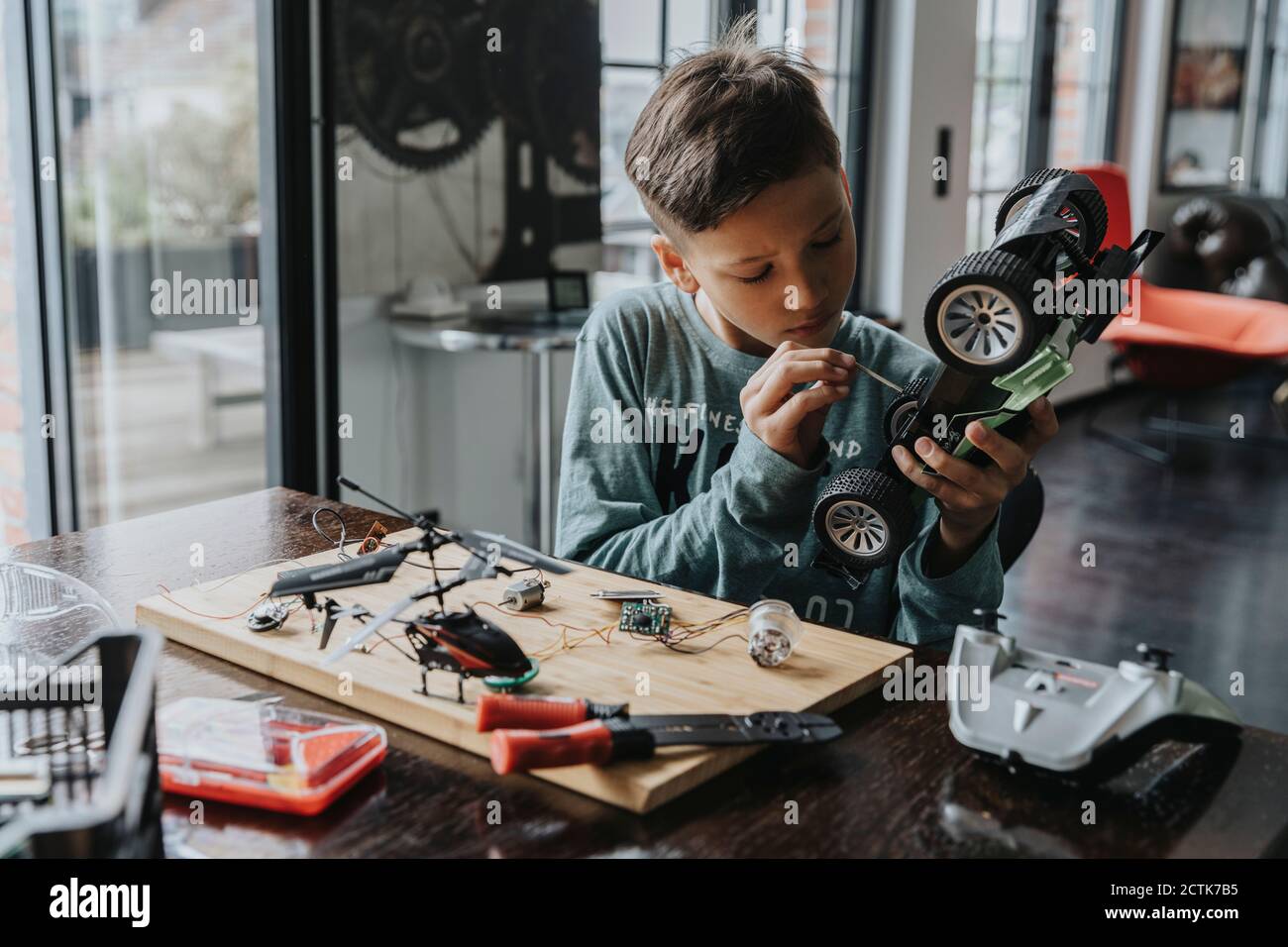 Boy assembling on remotecontrolled toy car with screwdriver Stock