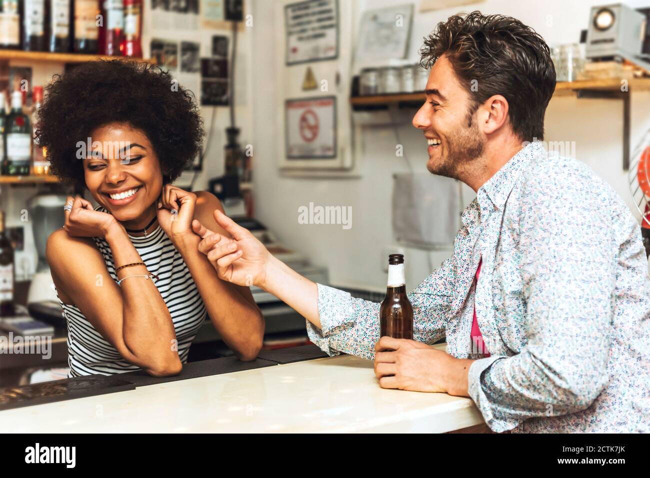 Man touching cheerful female bartender while flirting with her at bar
