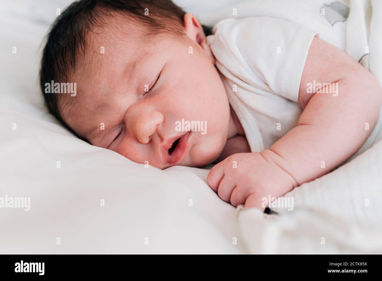 Close-up cute newborn baby girl sleeping on bed in hospital Stock Photo
