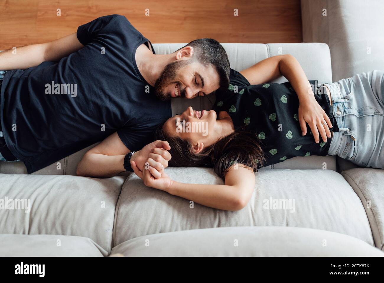 Couple relaxing while lying down on sofa at home Stock Photo