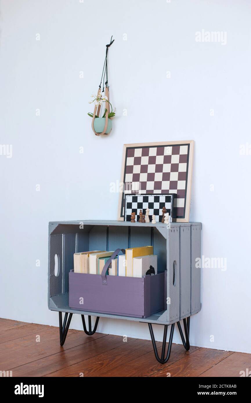 Chess boards lying on top of DIY bookshelf made of wooden crate Stock Photo
