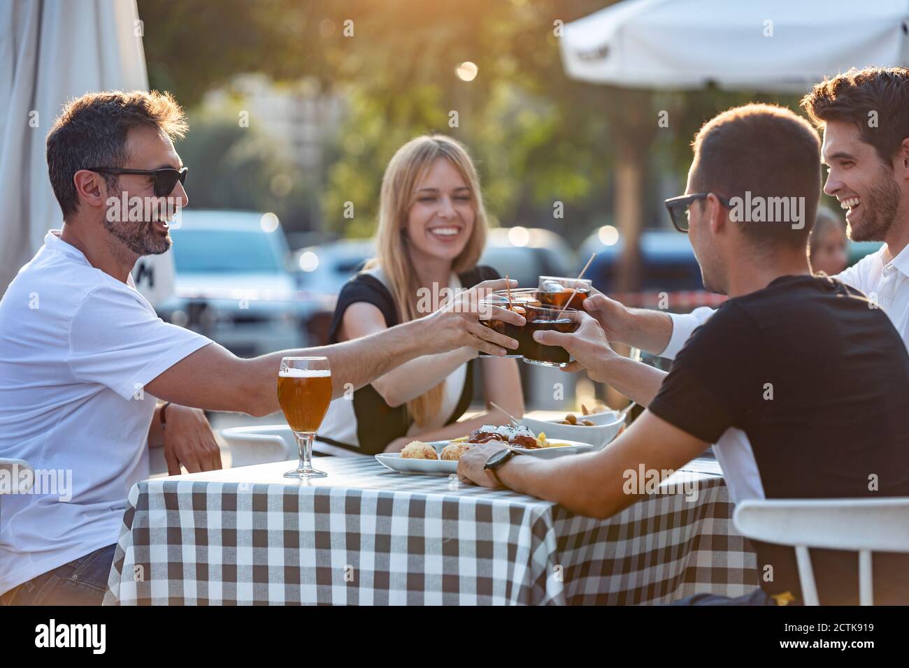 Friends toasting vermouth drink while enjoying meal at cafe Stock Photo