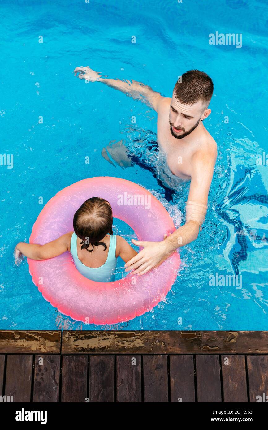 Little girl with floating tire and her uncle in swimming pool Stock Photo