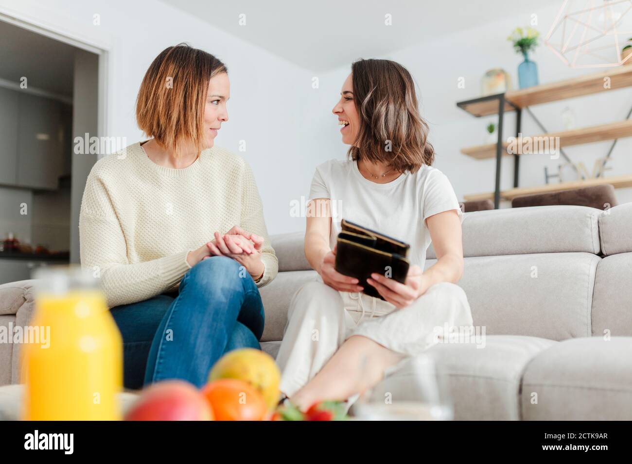 Smiling friends talking while using digital tablet at home Stock Photo