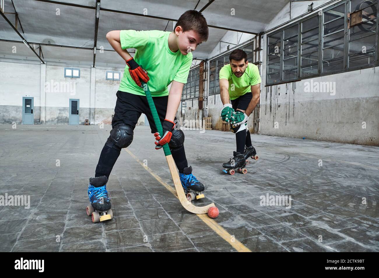 Boy practicing roller hockey with father on court Stock Photo Alamy