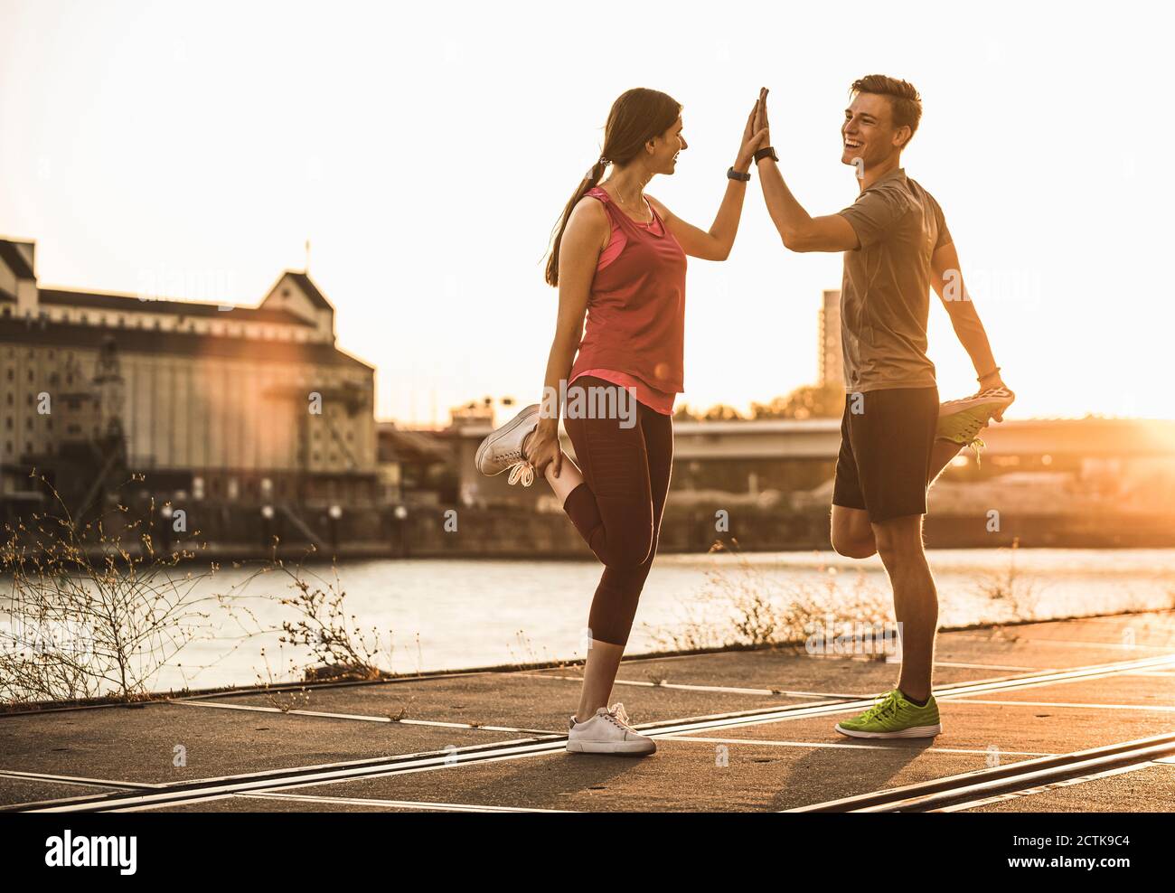 Friends exercising with hands clasped at harbor Stock Photo