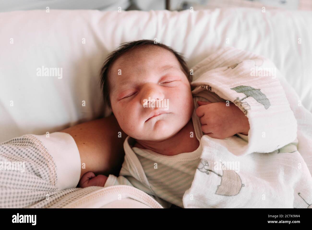 Close-up of newborn baby girl sleeping on mother's arm in hospital Stock Photo
