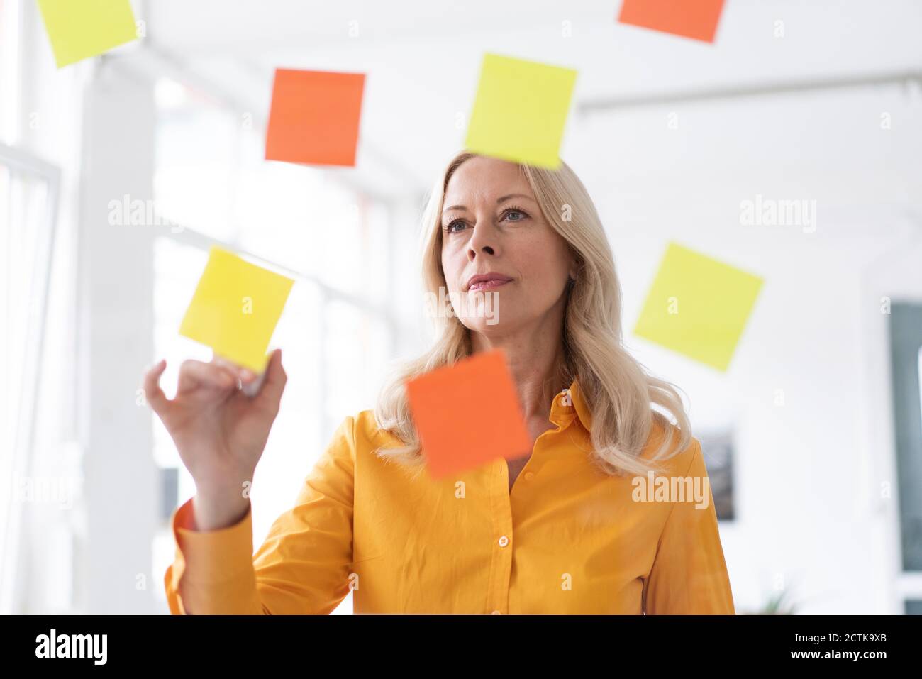 Businesswoman planning over adhesive notes stuck on window in home office Stock Photo