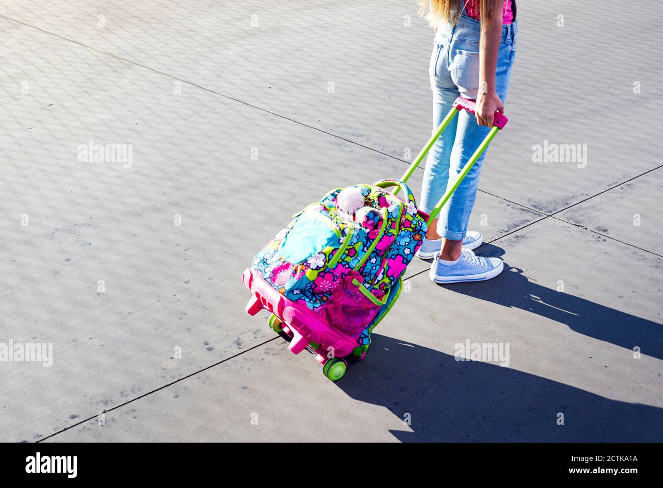 Girl standing with schoolbag on footpath Stock Photo