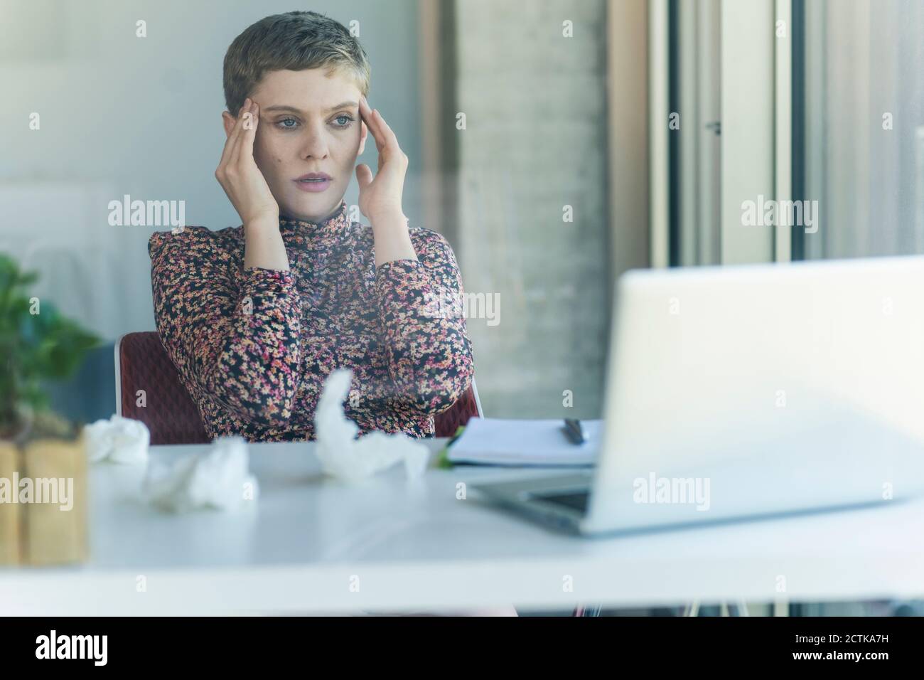 Businesswoman at desk in office having headaches Stock Photo