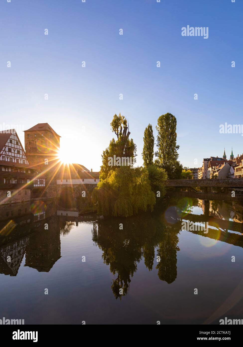 Germany, Bavaria, Nuremberg, Henkersteg, Weinstadel and Wasserturm reflecting in river Pegnitz at sunset Stock Photo