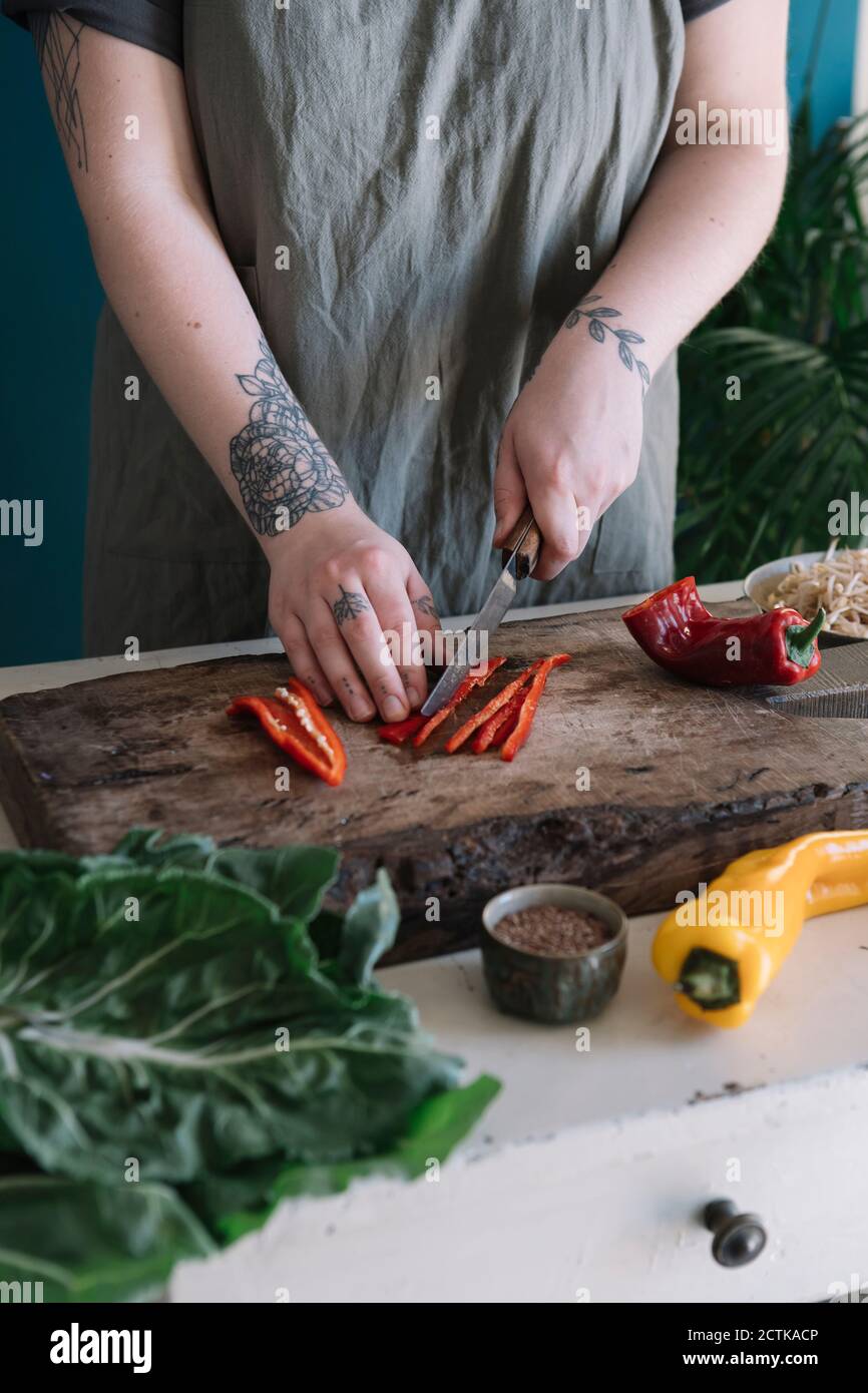 Young woman cutting bell pepper on cutting board Stock Photo