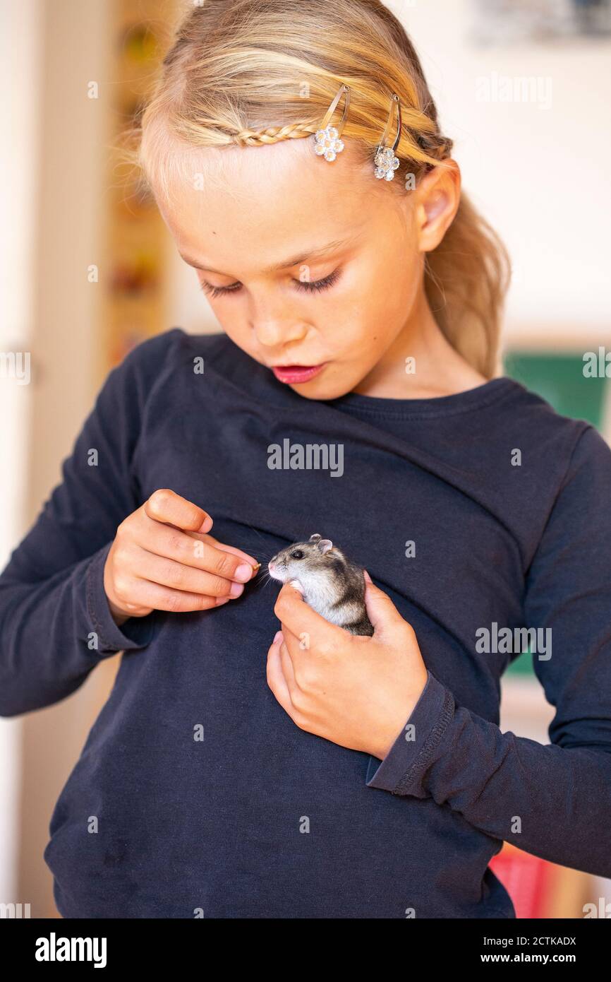 Blond girl feeding hamster Stock Photo