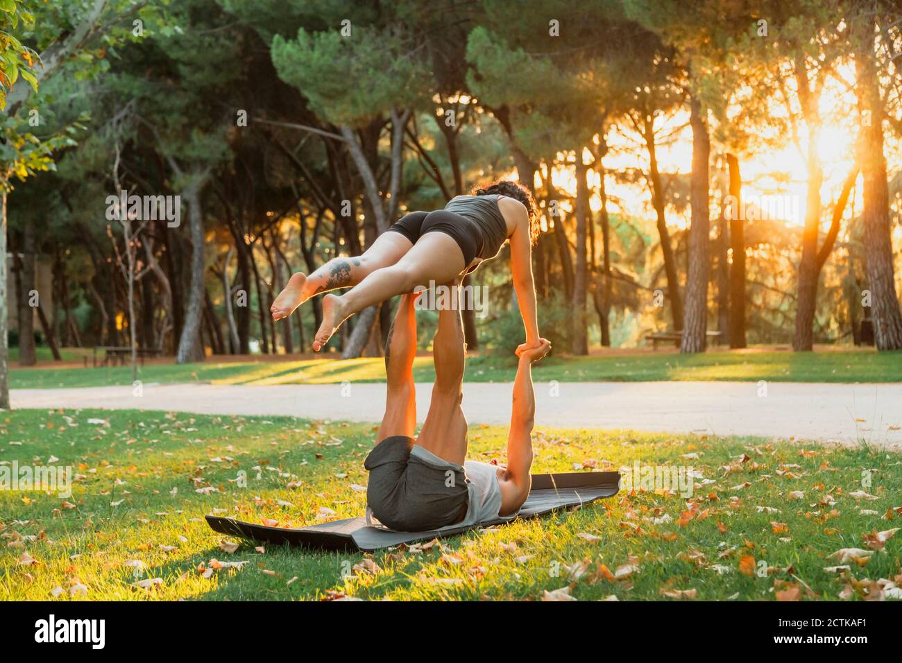 Male and female athletes practicing acroyoga in park during sunset Stock Photo