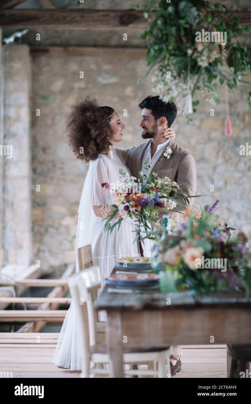 Bride and groom looking at each other while standing by wedding table Stock Photo