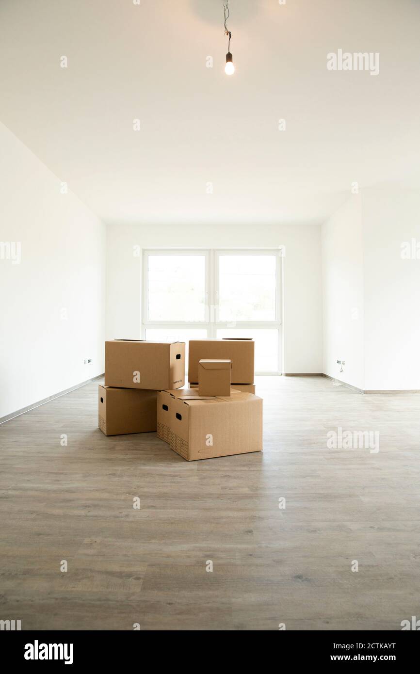 Light bulb hanging over cardboard boxes on hardwood floor in new house Stock Photo