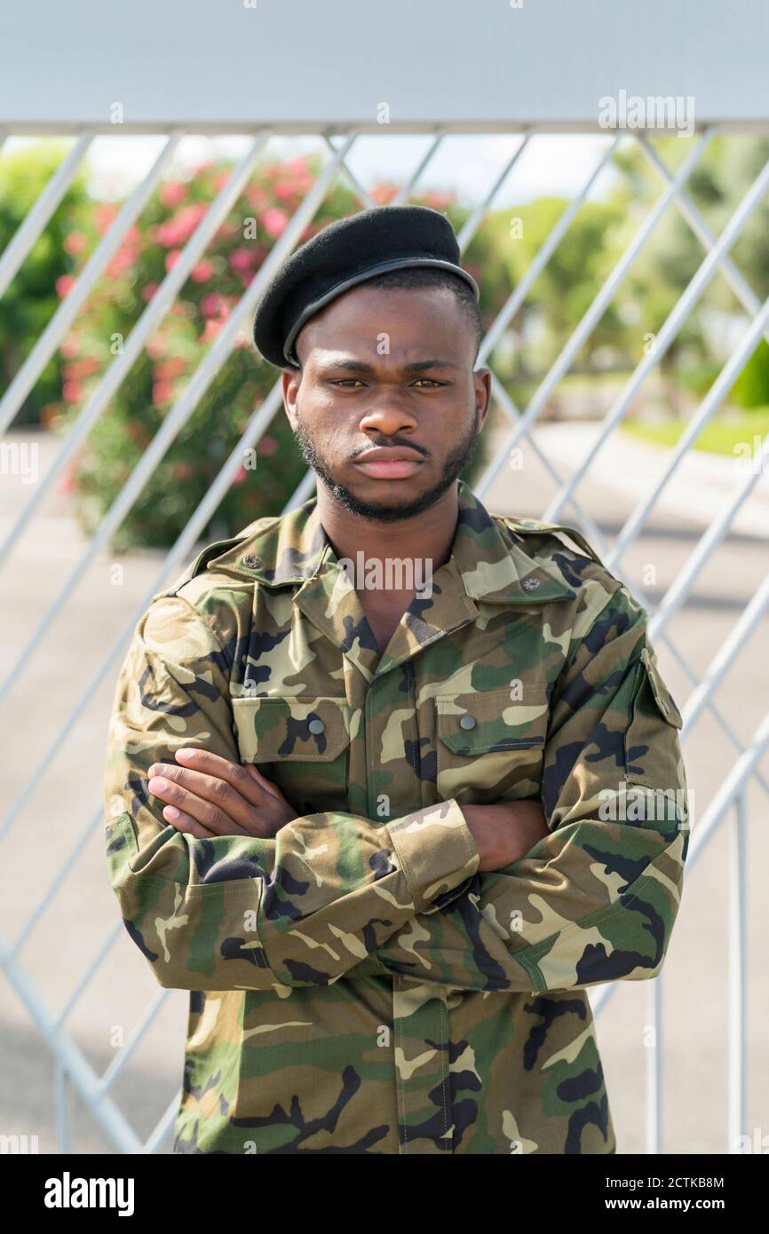 Army soldier standing with arms crossed against gate Stock Photo