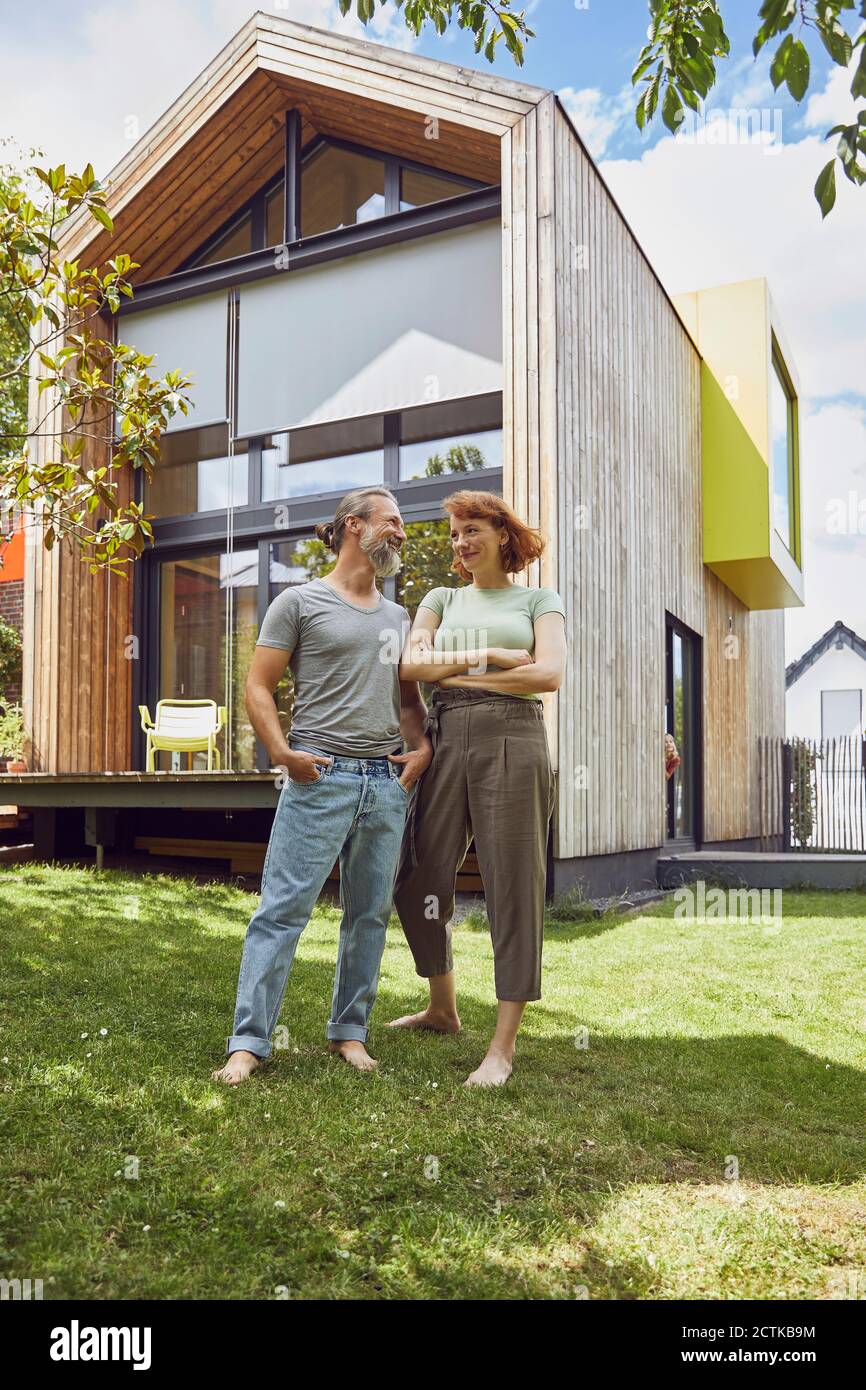 Mature man with hands in pockets looking at woman while standing outside tiny house Stock Photo