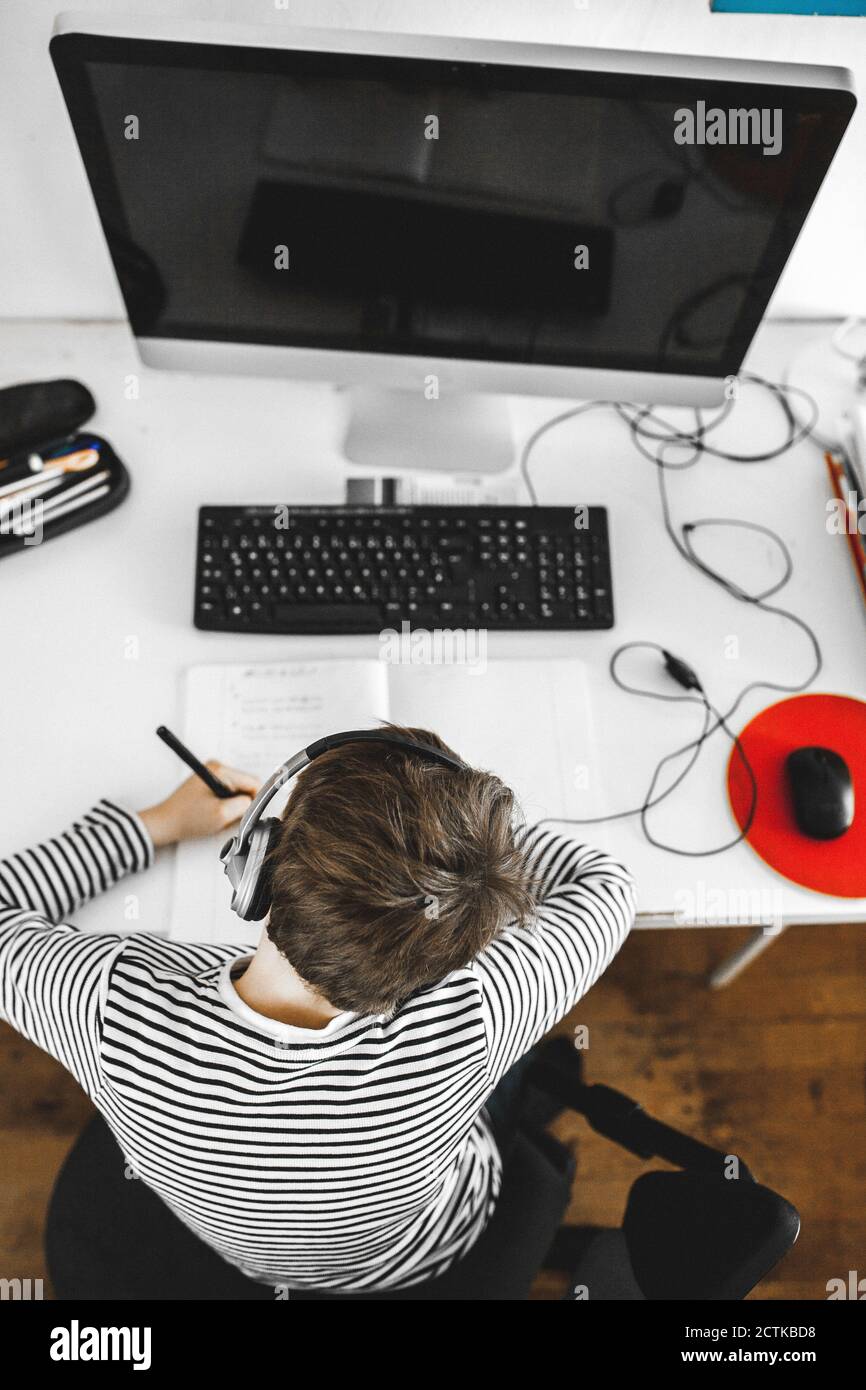 Boy doing homework on desk Stock Photo