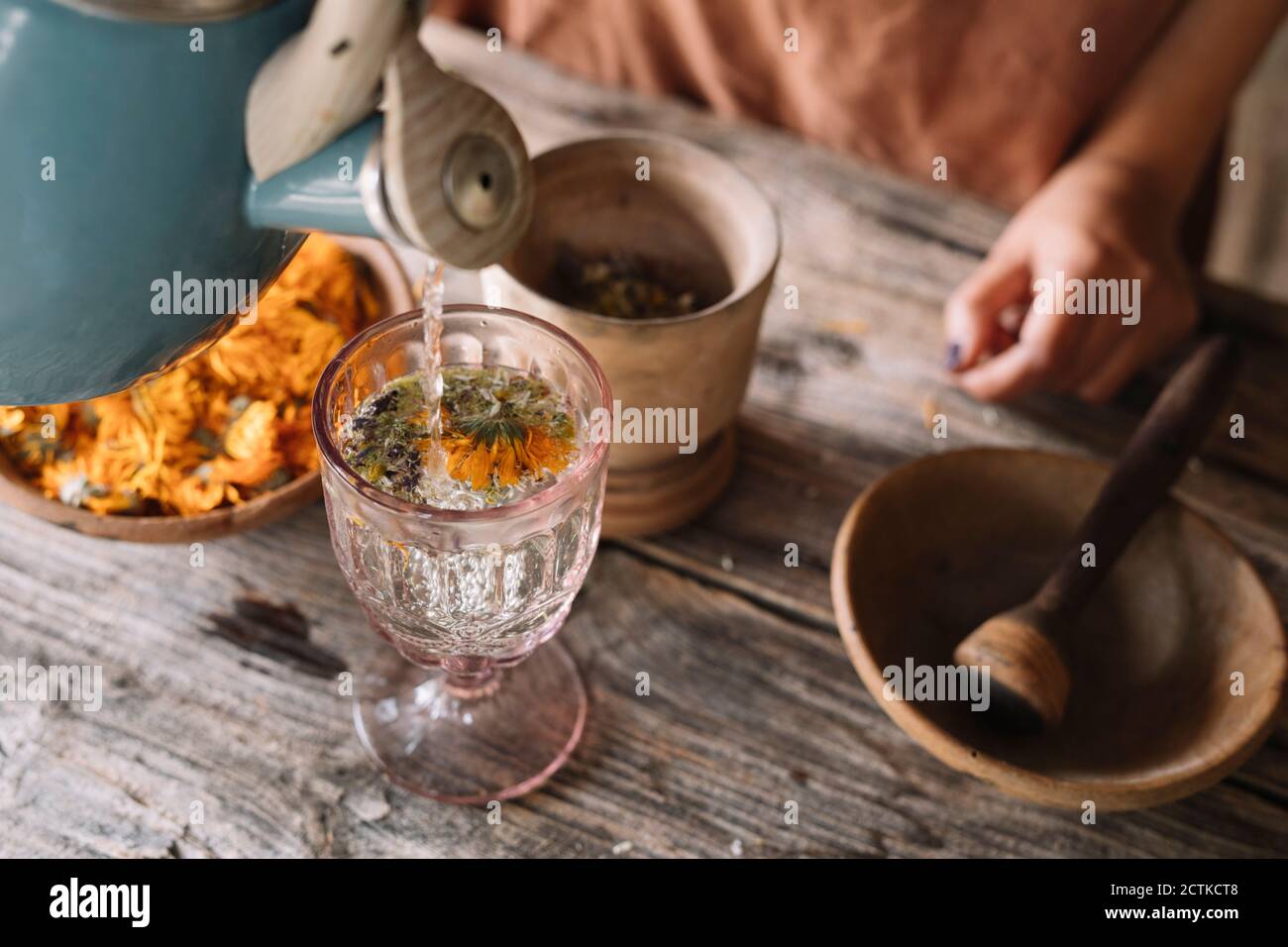 Teapot pouring hot water in herbal tea glass on table Stock Photo Alamy