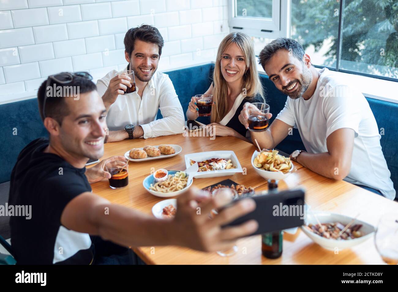 Group of friends taking selfie while having meal at restaurant Stock Photo