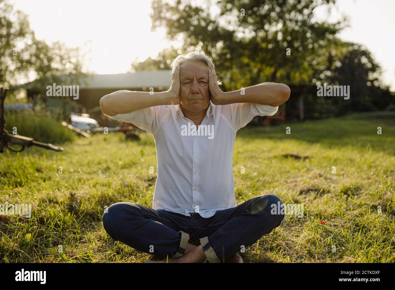 Man practicing yoga while sitting in backyard Stock Photo