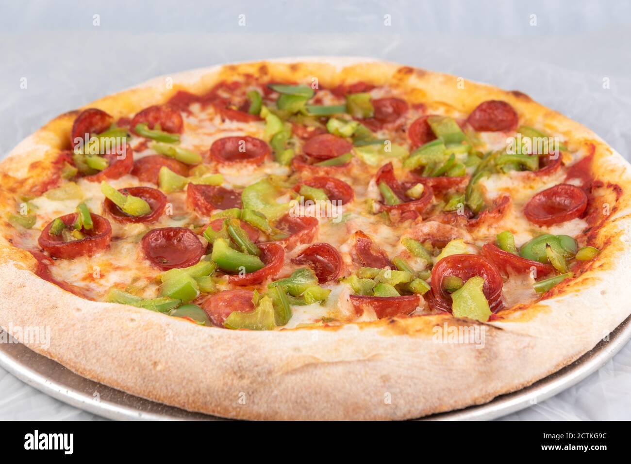 Healthy sized pepperoni and green pepper pizza with thick crust to