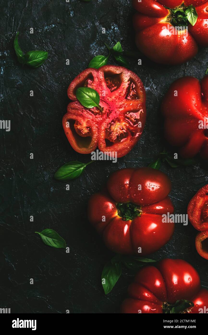 Red tomatoes with green basil leaves on the black kitchen table ...