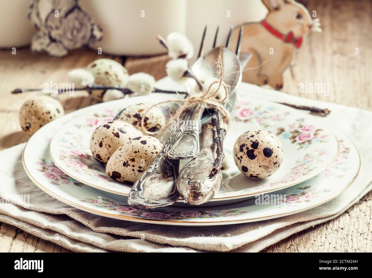 Served for Easter meal old table with plates, eggs and candles, selective focus Stock Photo