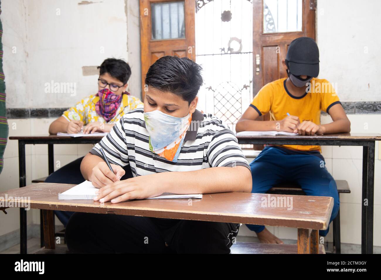 Indian Students wearing face masks maintaining social distancing at a classroom as school reopen during covid19 pandemic. Stock Photo