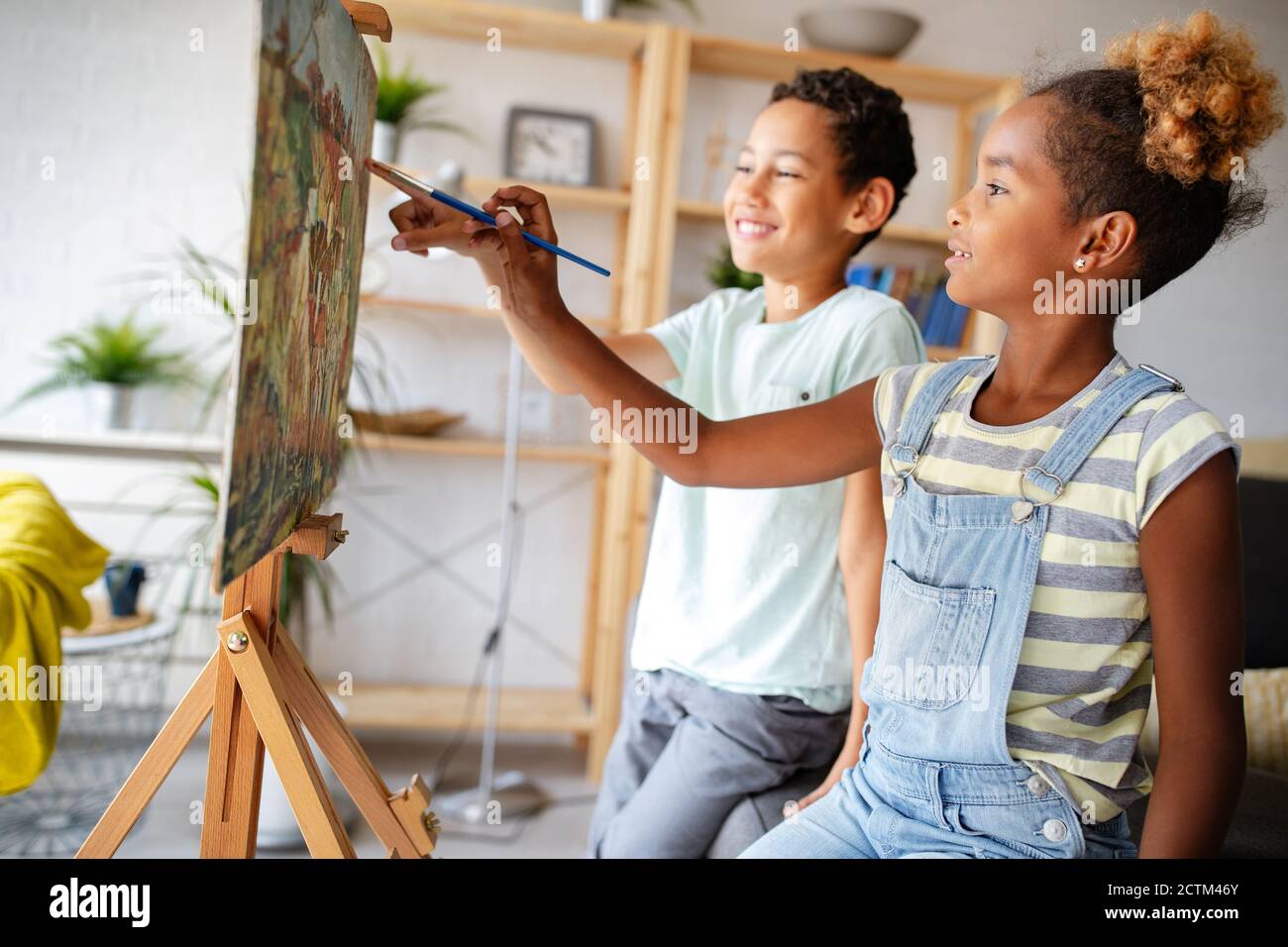 Cute children girl and boy painting together. Education, art, fun and creativity concept. Stock Photo