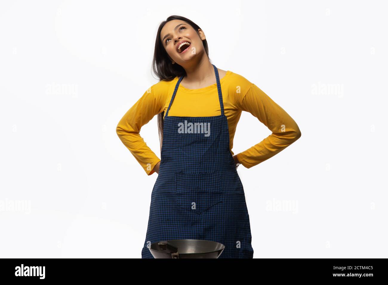 Young woman smiling while wearing an apron with a wok front Stock Photo