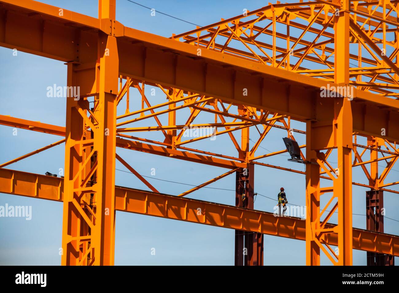 Kostanay/Kazakhstan - May 14 2012: Construction of new factory building. Assembling orange steel building structure. High-altitude worker (industrial Stock Photo