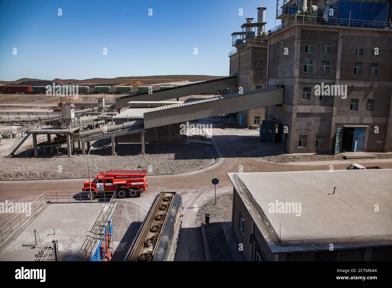 Mynaral/Kazakhstan - April 23 2012: Jambyl Cement plant. Factory buildings, conveyor, red fire truck and  cargo train. Panorama view. Stock Photo