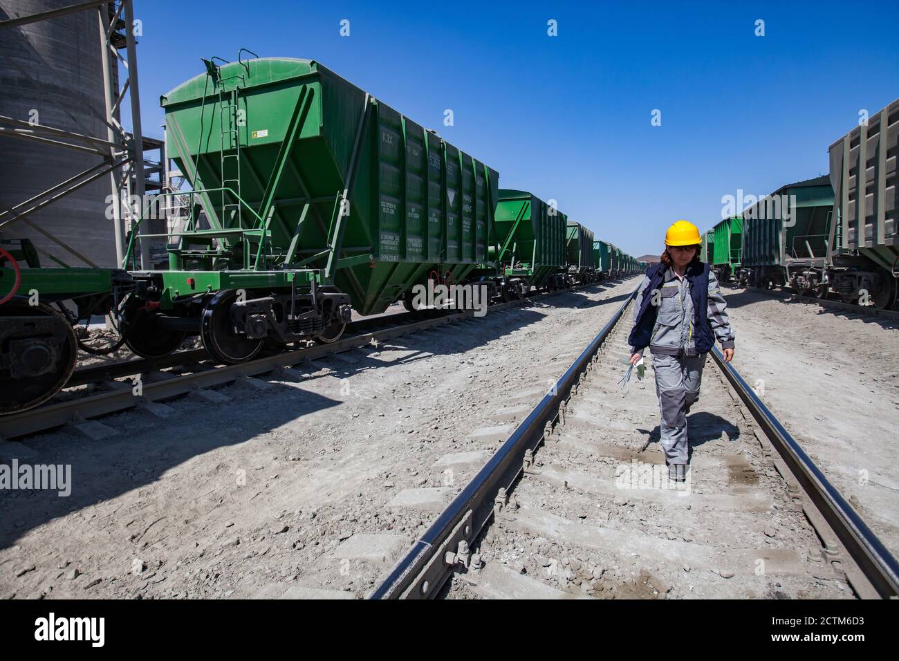 Mynaral/Kazakhstan - April 23 2012: Jambyl Cement plant. Cargo railway terminal. Worker women in yellow hard hat and work wear on the rails. Stock Photo