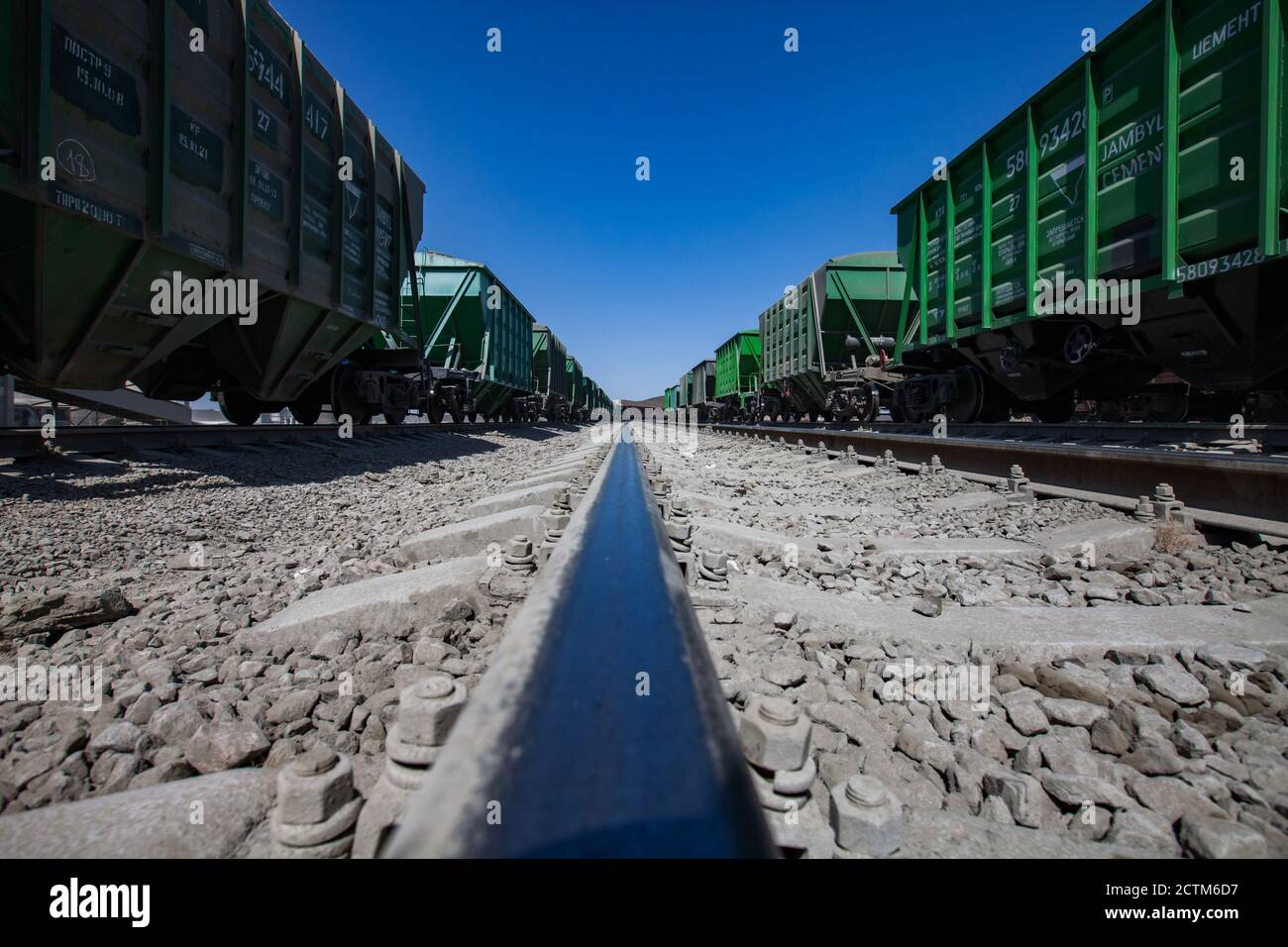Mynaral/Kazakhstan - April 23 2012:  Jambyl Cement plant. Cargo railway terminal. Close-up of rail. No one. Train cars in desert and dust. On deep blu Stock Photo