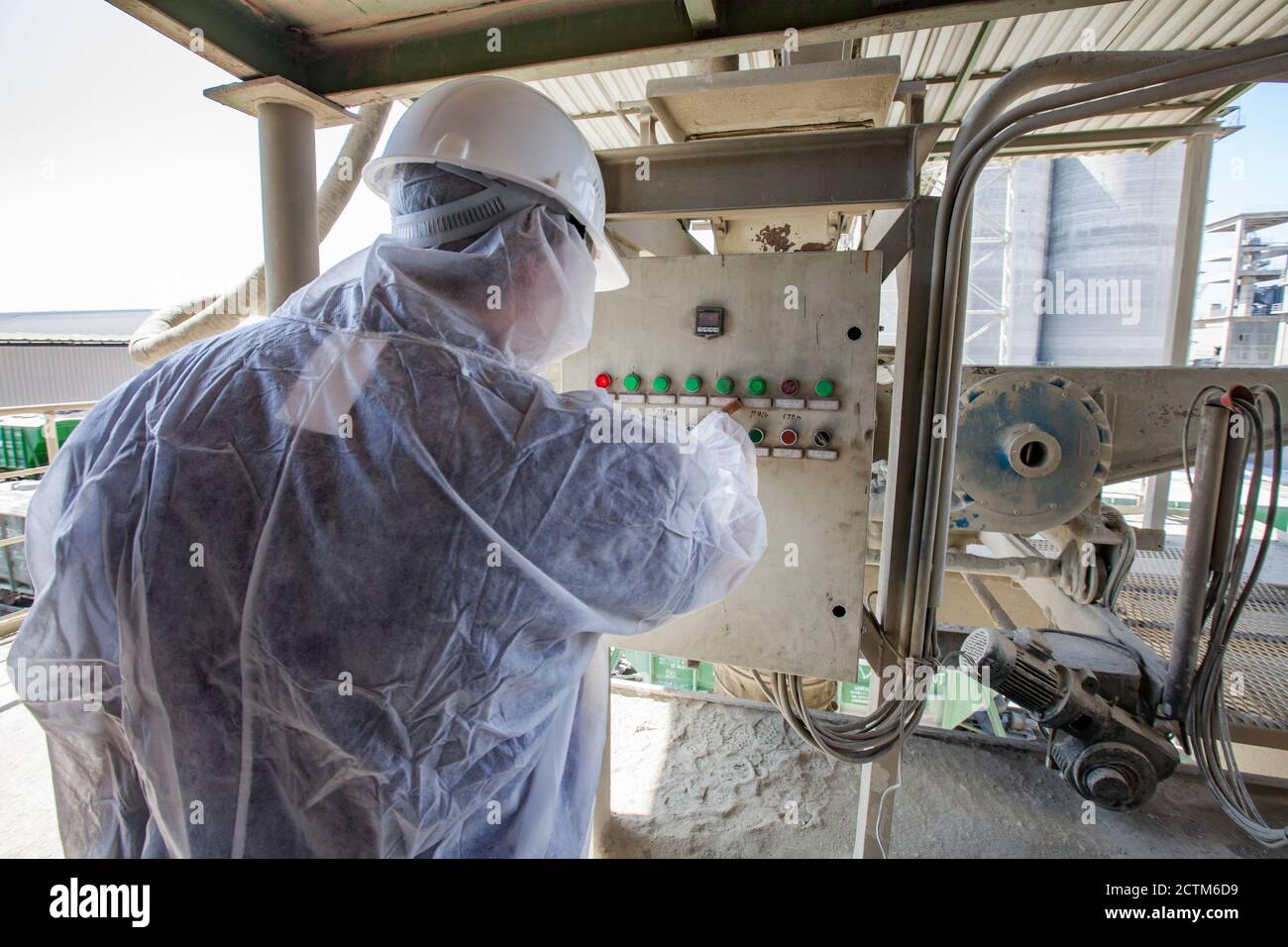 Mynaral/Kazakhstan - April 23 2012: Jambyl Cement plant. Engineer or worker in protective suit and white hard hat making an operation. Stock Photo