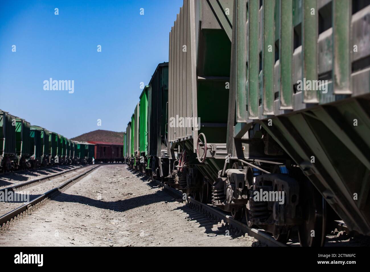 Mynaral/Kazakhstan - April 23 2012: Cement plant Jambyl Cement. Cargo railway terminal. Close-up rail wagons with rails on blue sky in desert. Stock Photo
