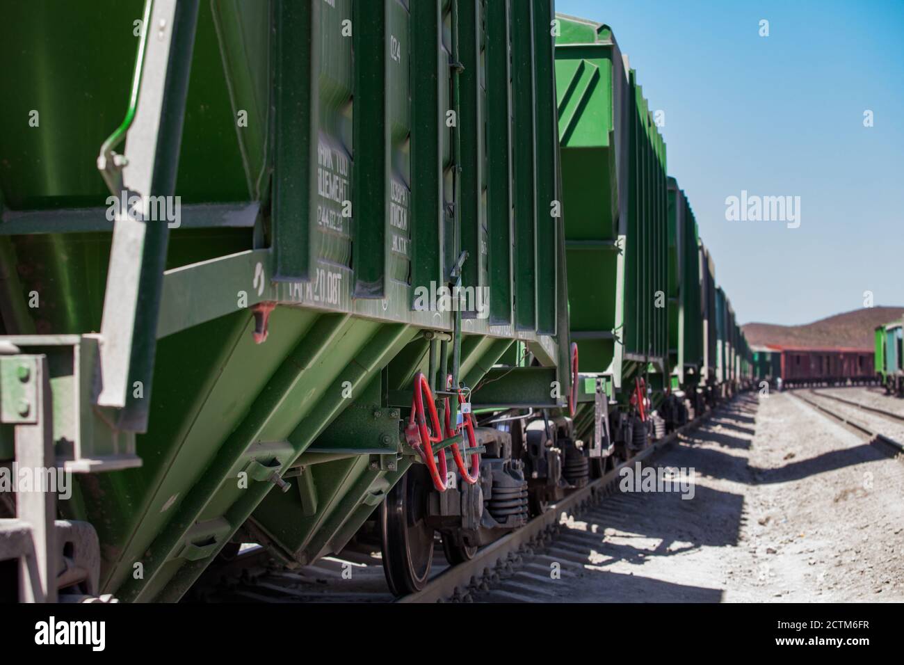 Mynaral/Kazakhstan - April 23 2012: Jambyl Cement plant cargo railway terminal. Close-up rail wagons with hopper in desert on blue sky background. Stock Photo