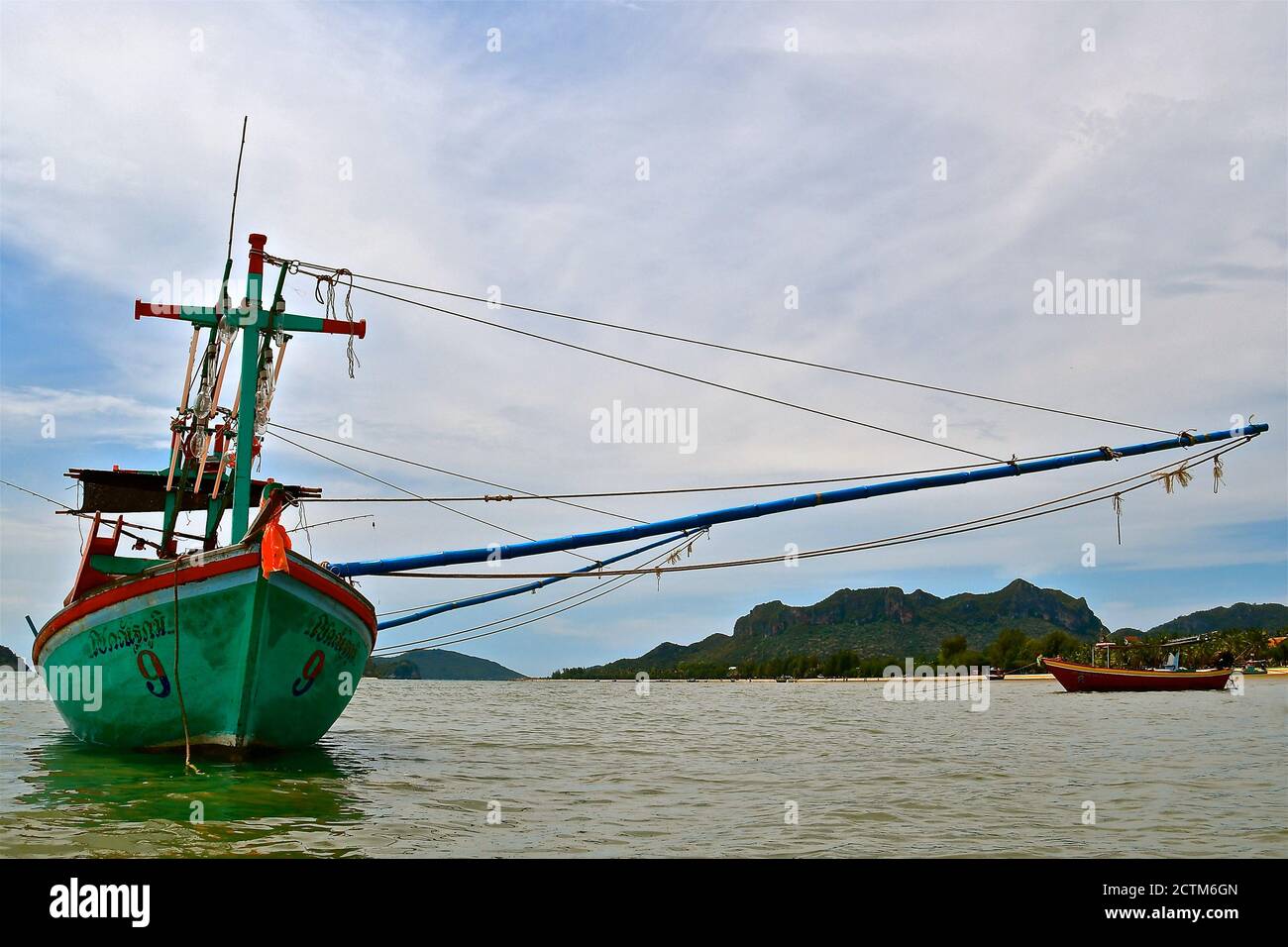 Green wooden traditional fishing boat moored in a bay in a tropical island setting. Stock Photo