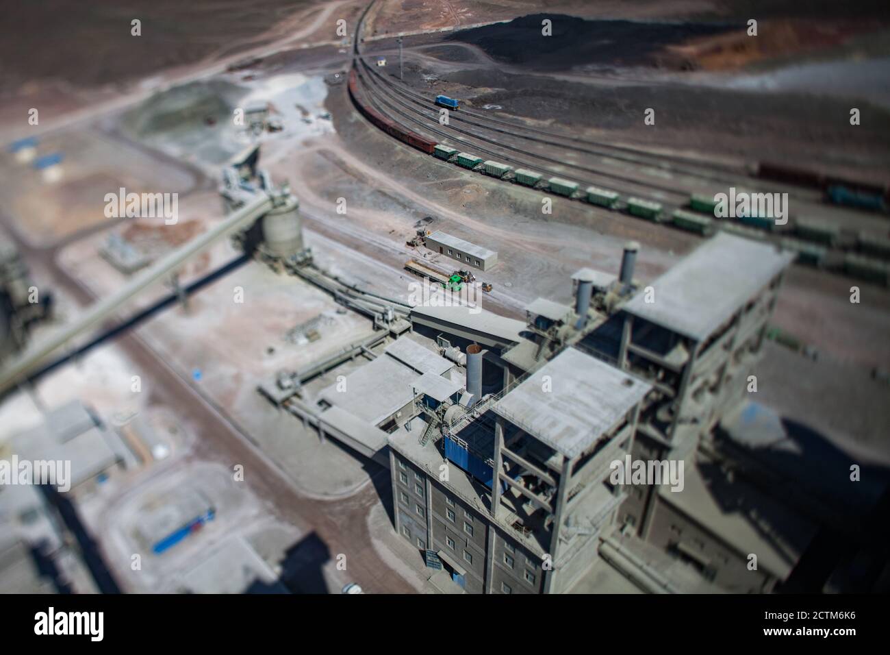 Mynaral/Kazakhstan - April 23 2012: Jambyl Cement plant. Aerial view on long truck on railway terminal and factory buildings. Tilt-shifted view. Stock Photo