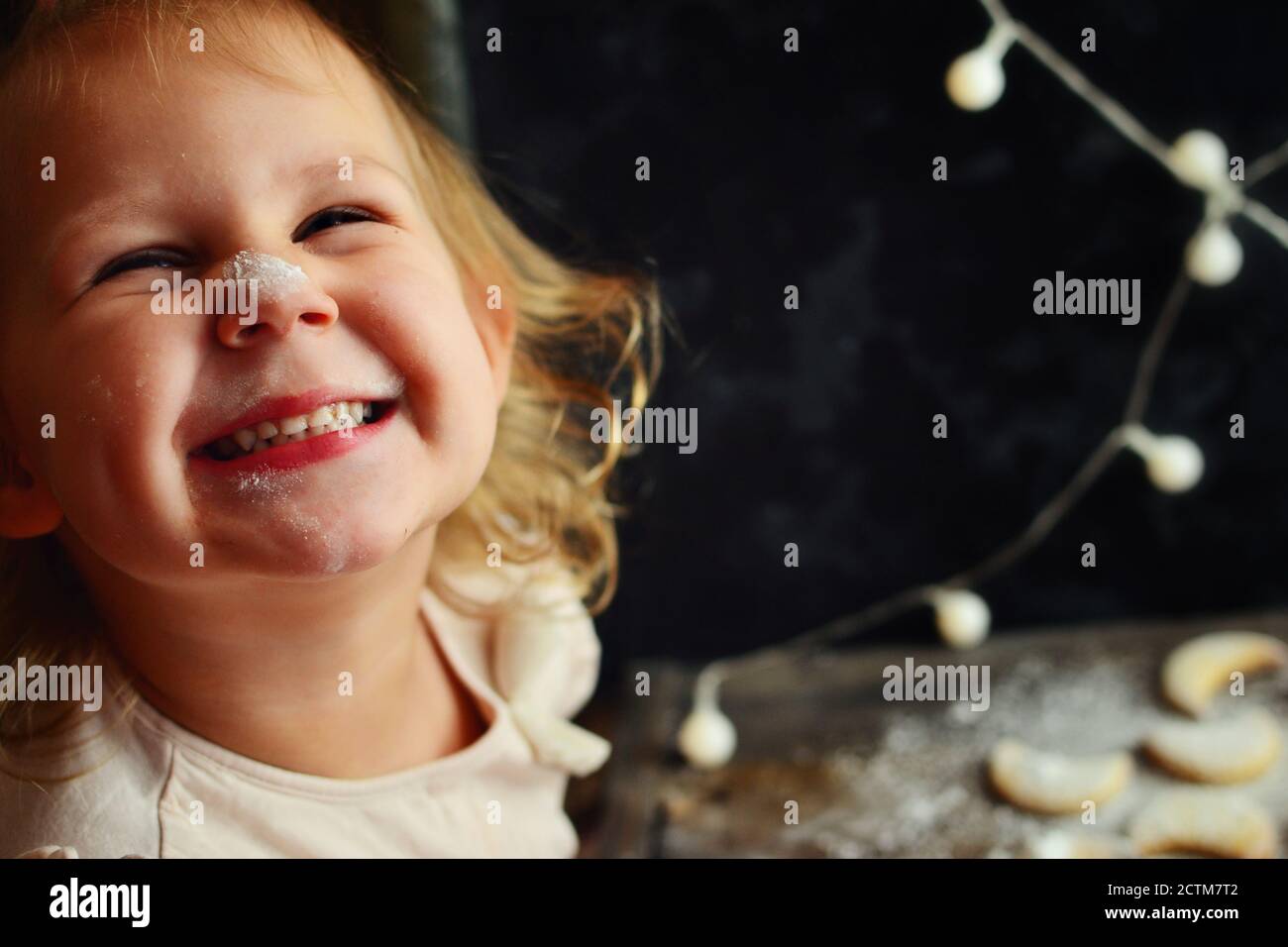 Portrait of a beautiful child 2-3 years old. Baby is preparing New Year and Christmas cookies. Food and baby in the frame. A child sprinkles cookies Stock Photo