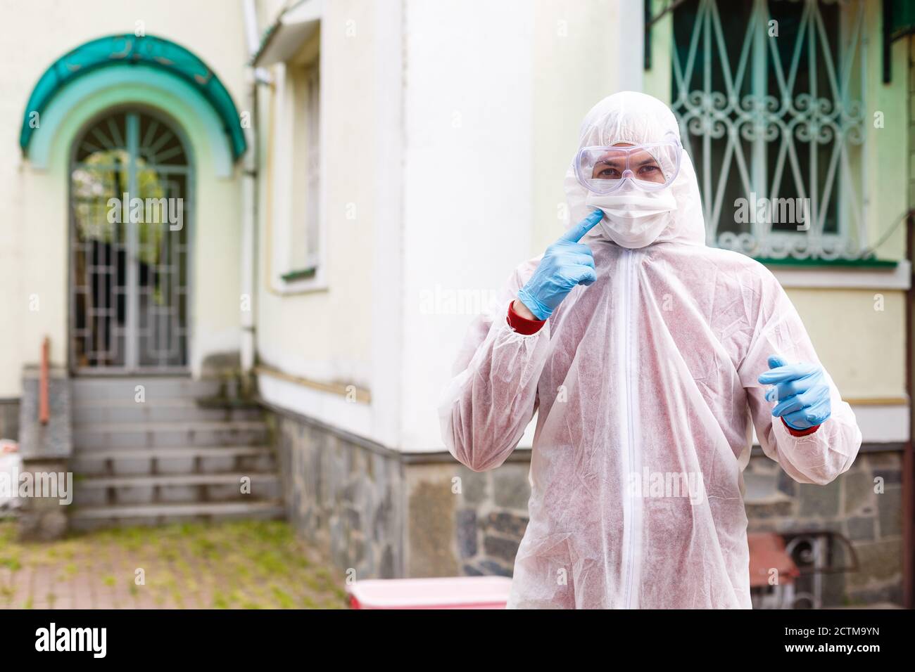 selective focus of smiling male scientist in protective mask and suit looking at camera outdoors Stock Photo