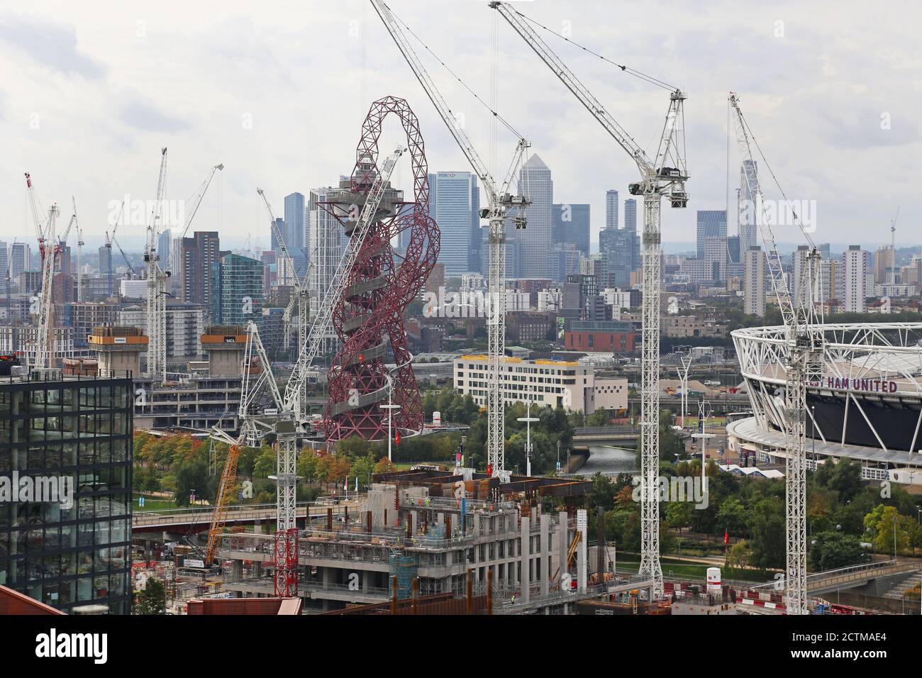 The Arcelor Mittal Orbit tower surrounded by cranes as the Stratford Olympic Village area is developed with new apartment blocks. Canary Wharf beyond. Stock Photo