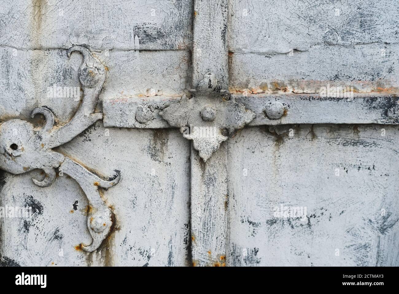 Fragment of ancient peeling and decayed monastery gates with rusty skillfully forged hinges and decorative overlays.  Stock Photo