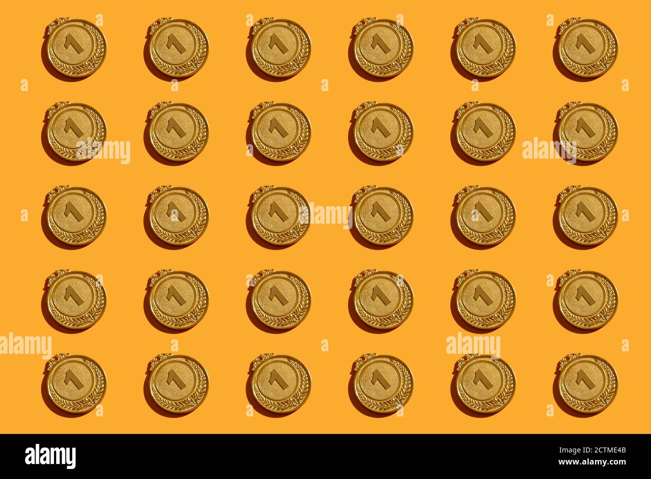 Pattern of gold medals with a hard shadow on a yellow background. Stock Photo