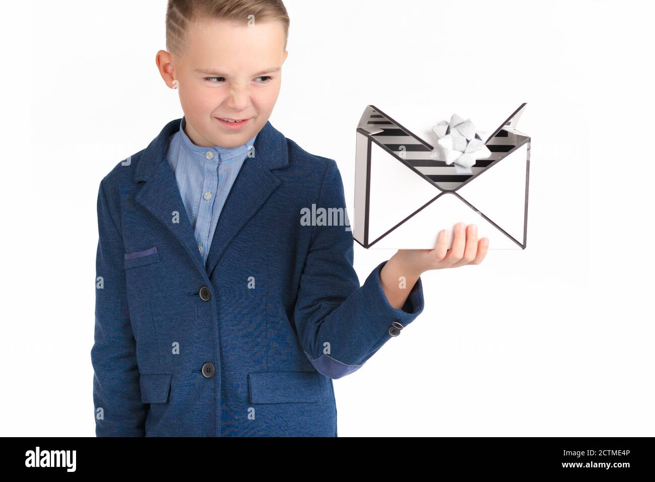 European boy in a blue costume looks at the empty gift box with disgust.White isolated background. Stock Photo