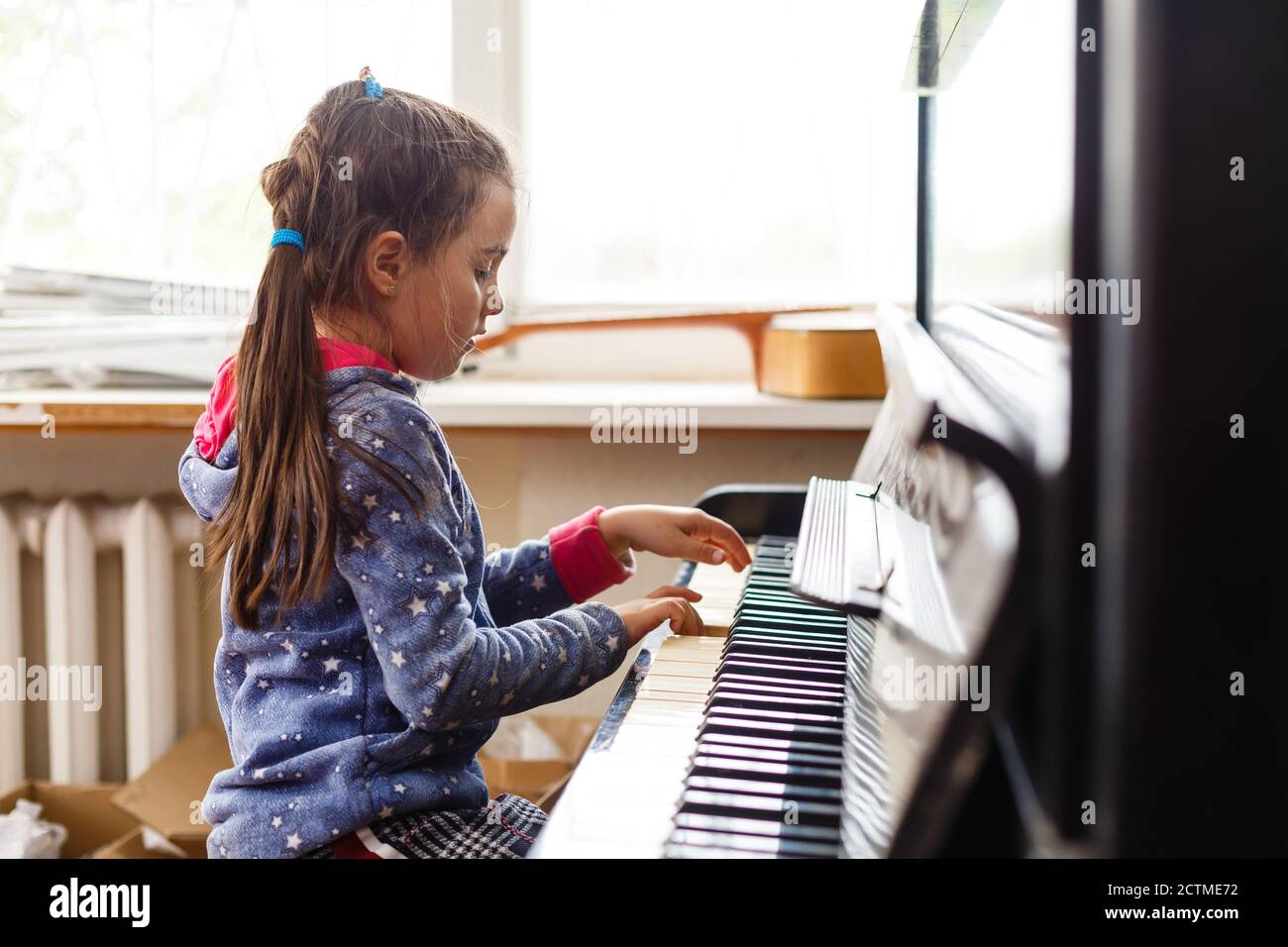 little girl plays the old piano in the old house Stock Photo
